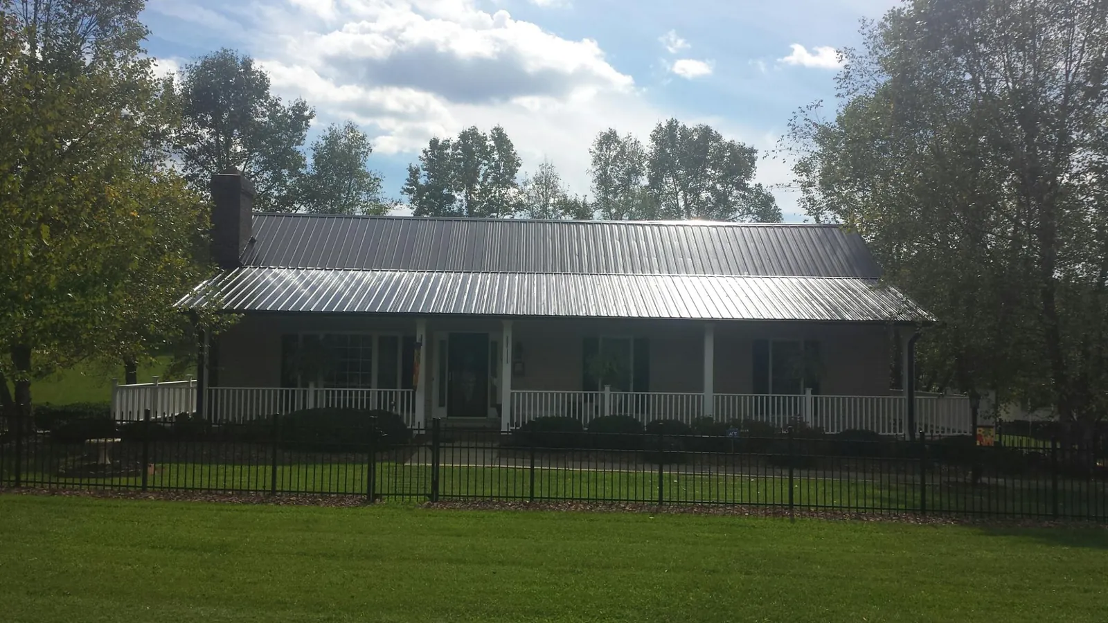 Gray metal roof on a brick ranch with a full width front porch — Gutter Guard Installation work by our crew in Firth